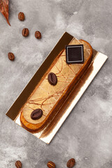 Eclair with coffee flavoured cream filling and chocolate on golden cardboard