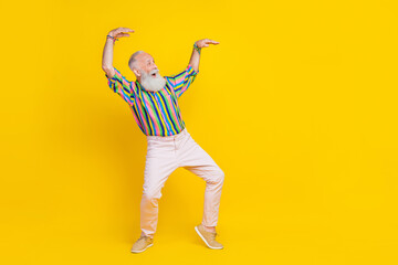 Fototapeta na wymiar Full length photo of charming positive guy dressed striped shirt dancing looking empty space isolated yellow color background