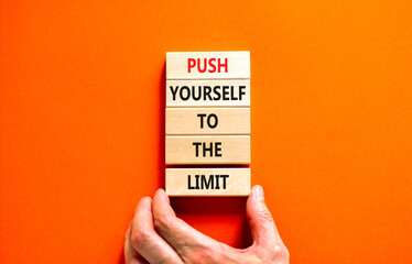 Push the limit symbol. Concept words Push yourself to the limit on wooden blocks. Beautiful orange table orange background. Businessman hand. Business push the limit concept. Copy space.