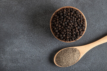 Ground black pepper with grains of black pepper on a dark background,top view