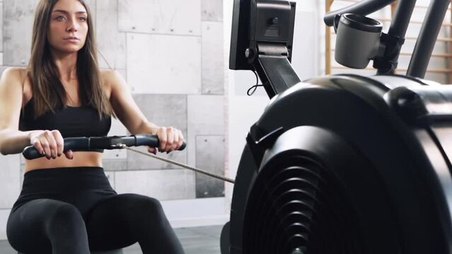 Young woman trains at the rowing machine
