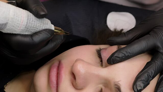 the master holds with his fingers and applies the tattoo on the lashes of the model. permanent makeup procedure. High quality 4k footage