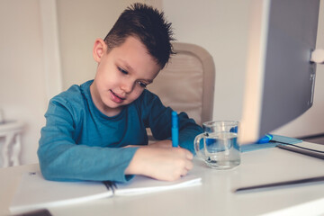 Young boy in the living room sitting at desk doing homework.