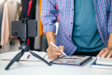 Asian man blogger using tablet computer sell products online and streaming it via mobile phone to introduce customers, New business and working at home concept