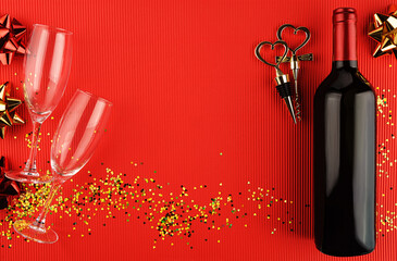 Still life with a bottle of wine, a corkscrew and a cork with heart-shaped handle on red background. View from above.