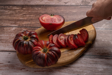 woman's hand with knife cutting tomatoes on a board