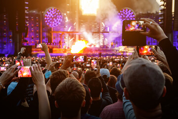 Hand with a smartphone record live music festival and taking photos of the concert.