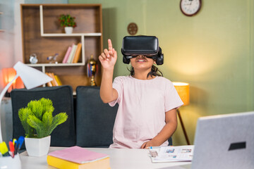 Girl kid with vr or virtual head set listening online or virtual class in front of study table at...