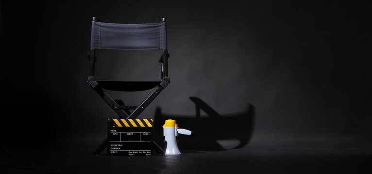 Back Of Black Director Chair And Yellow Clapper Board With Megaphone On Black Background.