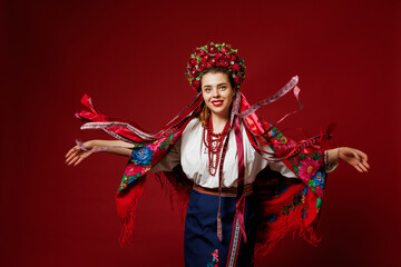 Portrait of ukrainian woman in traditional ethnic clothing and floral red wreath on viva magenta studio background. Ukrainian national embroidered dress call vyshyvanka. Pray for Ukraine