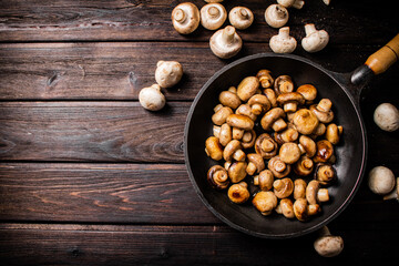 Delicious small fried mushrooms in a frying pan. 