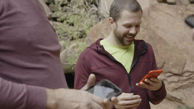 Close up of smiling men with cell phones talking in Zion National Park / Springdale, Utah, United States
