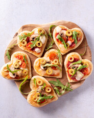 Heart shape mini pizzas on wooden board for Valentines day holiday, top view