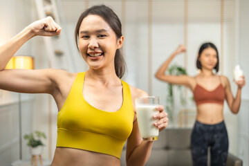 Attractive fitness asian woman finishing workout and drinking protein milk shake vitamins after training at home. Bodybuilding. Healthy lifestyle.