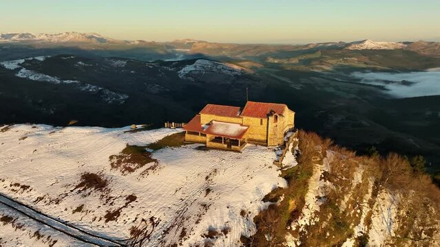 4k aerial view Hermitage in Kolitza mount in Balmaseda at dawn with snow, Basque Country, Spain