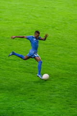 Vertical Shot: Major League Soccer Football Championship. Portrait of Blue Team Player Running, Determined to Win. Live Sport Channel, Broadcast Television. Black Player Kicking the Ball to Score