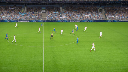 Soccer Football Championship Stadium with Crowd of Fans: Blue Team Attacks, Forward Dribbles, White Team Defending The Goals, Ready To Counterattack. Sports Channel Broadcast Television. High Angle.