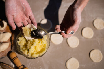 Sculpt dumplings. Hands of a person. Make dumplings in the kitchen. Dough for dumplings. Ukrainian traditional dish. 