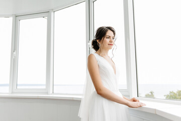 beautiful bride in a bright interior looks out the window
