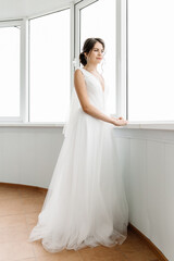 portrait of the bride at the window in full growth on the balcony