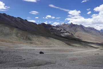Fototapeta na wymiar Ladakh, India - August 24th, 2022: Offroad vehicle goes on the mountain on empty road of ladakh