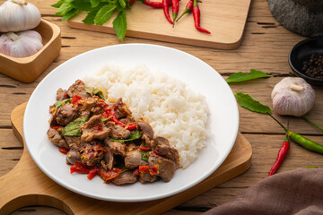 Stir-fried Chicken Giblets(livers, heart and gizzards) with Chillies and basil in white plate with cooked rice