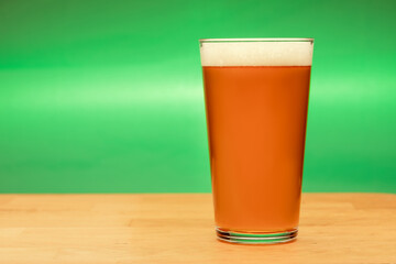 Full shaker pint glass of ale or beer on a table