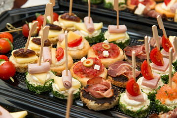 The buffet at the reception. Assortment of canapes. Banquet service. Catering, snacks with different types of cheese and meat. Party Concept.