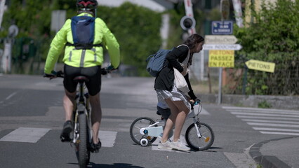 Fototapeta na wymiar Mother helping child cross street riding bicycle