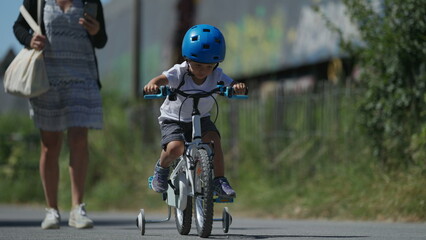 Naklejka premium Small boy riding bicycle outside child rides bike wearing helmet