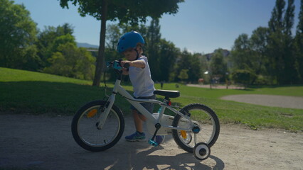 Child stepping off bicycle and carrying bike at park