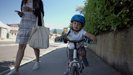 Fototapeta premium Active child riding bicycle outside on street sidewalk