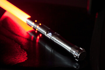 Close-up of red colored illuminated laser sword with grip against black background. Photo taken January 24th, 2023, Zurich, Switzerland.
