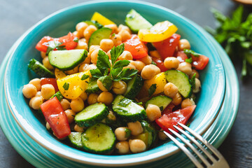 Chickpea salad with tomatoes, cucumber, parsley, onions in a plate, selective focus. Healthy vegetarian food, oriental and Mediterranean cuisine. Chick peas salad