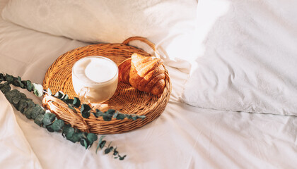 Tray with croissants on white bed linen.
