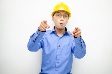asian construction worker wearing yellow safety helmet and smiling and pointing finger with happy and shocked expression. billboard model advertisment concept. construction worker presenting something