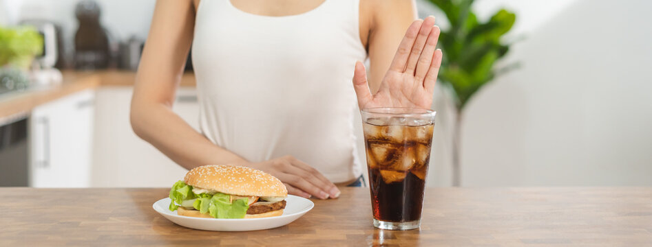Diet, Dieting hand of asian young woman deny, avoid hamburger, junk or fast food and sparkling water, soft drink, eat food for good healthy, health when hungry. Temptation of weight loss people.
