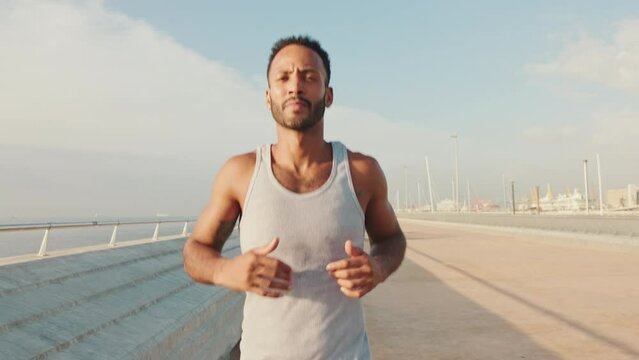 Young bearded male fit athlete runs along the promenade