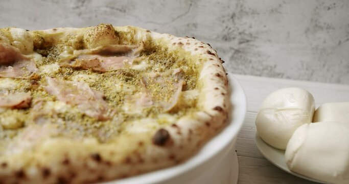 Pizza with Meat, Pesto, Cheese and Parmesan fresh out of the oven ready to eat. Delicious Italian pizza. Napoli Pizza. Food Service on white table and ingredient. Tasty Pizza with Cheese and Parmesan.