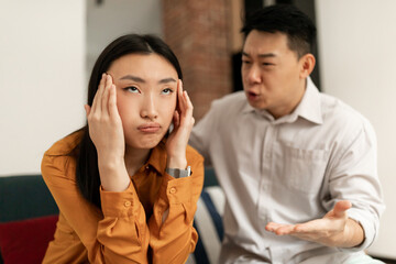 Fototapeta na wymiar Emotional japanese mature man gesturing and shouting at his wife, chinese couple having quarrel at home