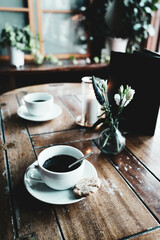 Two coffee cups on an old wooden table. Cups with cookies during a morning break. Elegant hotel service. Coffee at the window, silence and peaceful life. Coffee and snack time.