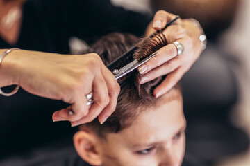 Cute young boy getting a haircut by hairdresser