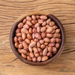 Raw peanuts in a bowl over wooden table