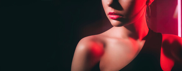 Fashion beauty. 90s look. Retro vogue. Red color neon light cropped profile portrait of unrecognizable woman model face on dark black copy space background.