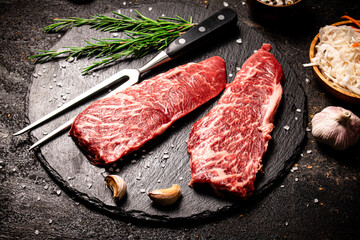 Raw steak on a stone board. On a black background.