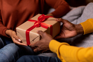 Cropped of black man and woman exchanging presents at home