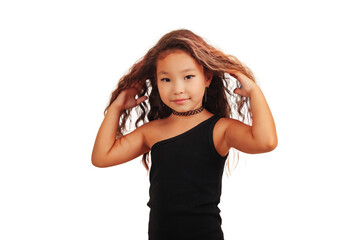 Obraz na płótnie Canvas Funny asian little girl with long curly hair posing at empty background, looking at camera. Studio shot stylish pretty small stylish model. Fashion education concept. Copy text space for advertising