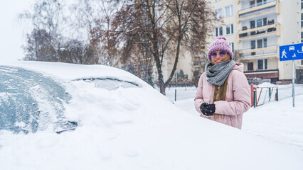 Fototapeta na wymiar Woman in sunglasses standing next to the car burried under the snow . High quality photo