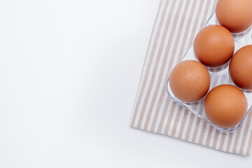 Chicken eggs on a transparent stand, there is a kitchen towel next to it. copy space