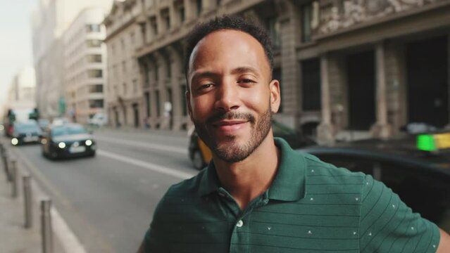 Close-up of happy young man standing on the street. Guy turns his head and smiles at the camera
